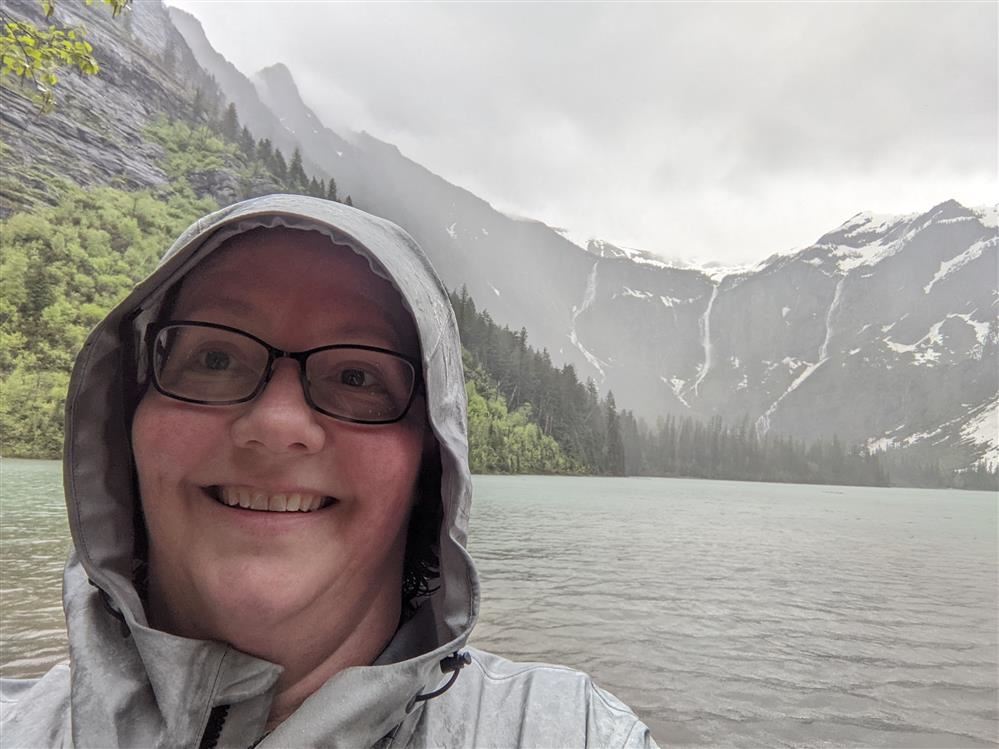 Ms. Coffman standing in a downpour in front of Avalanche Lake in GNP